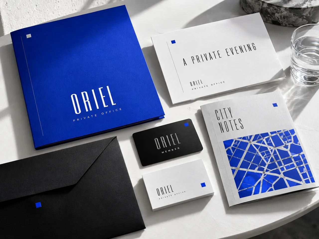 ORIEL studio concept: a cobalt folder, invitation, black member card, business cards and city notes