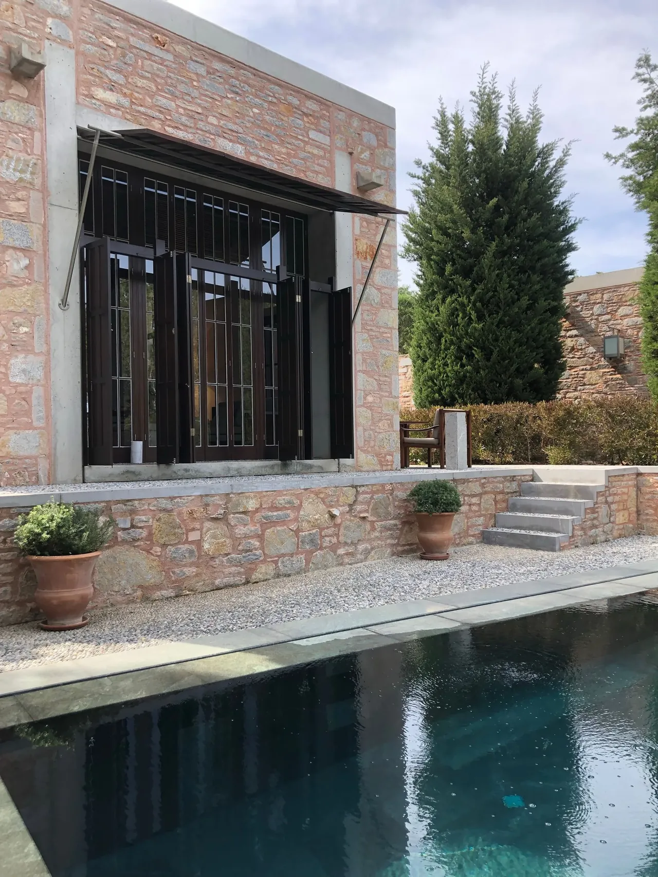 A stone residence with a dark pool and steel-framed windows